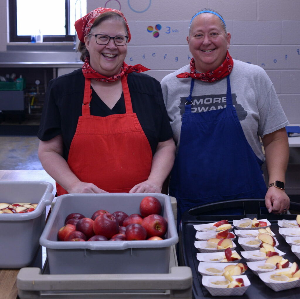 Clear Creek Amana district food director Debbie Klein (left) and Amana Elementary kitchen manager Rebecca Berstler (right) with locally grown apples