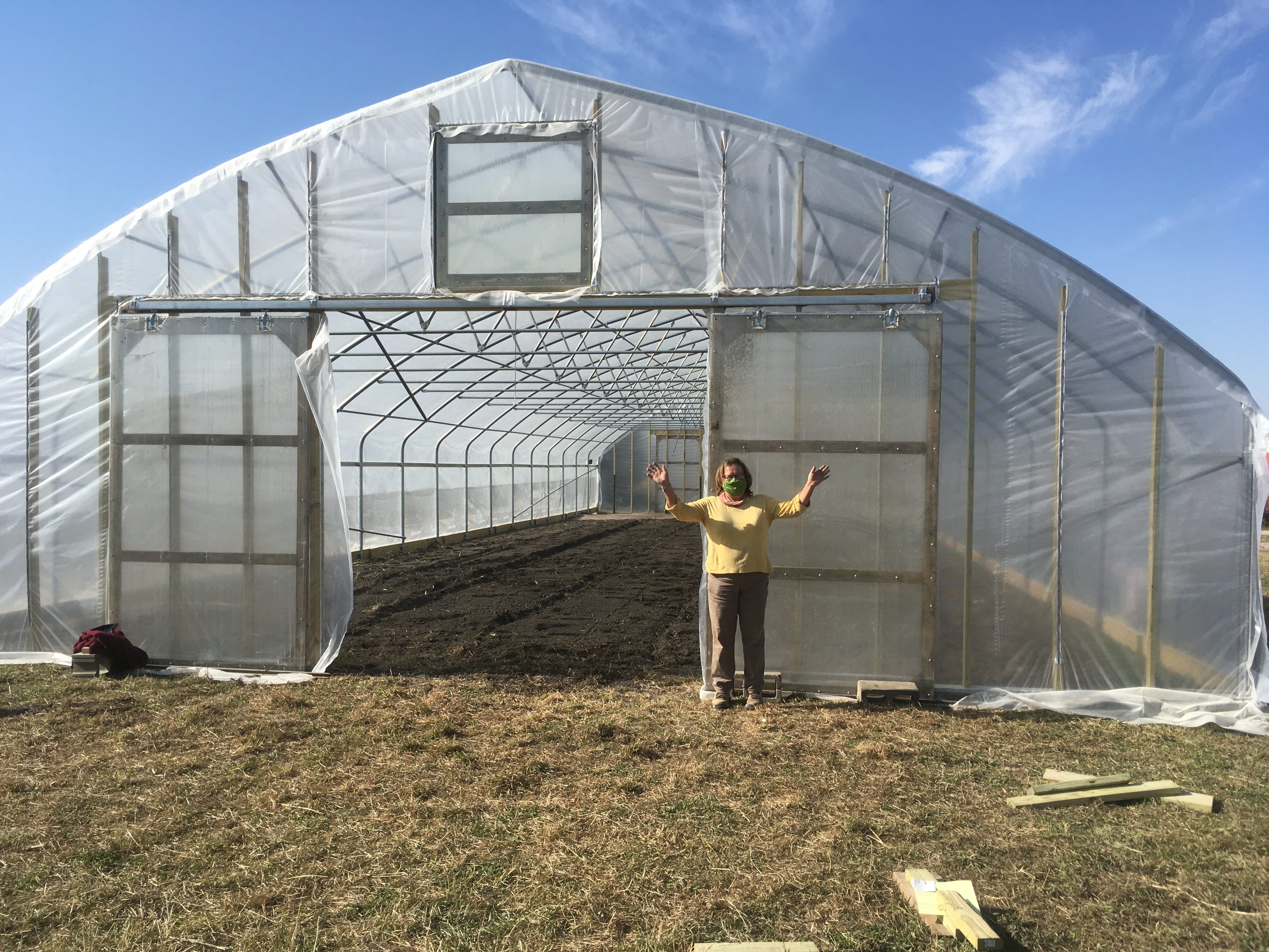 Laura Krouse standing by her newly finished high tunnel sent by Kate Edwards