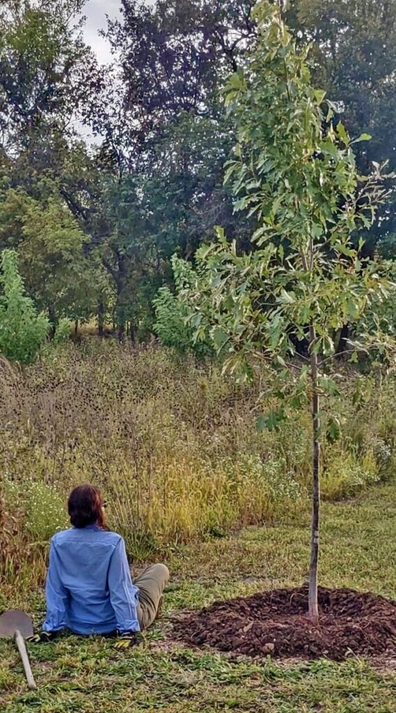 Ruth takes a break after planting a white oak on her farm. Each of her trees has been handplanted and watered with rain barrels