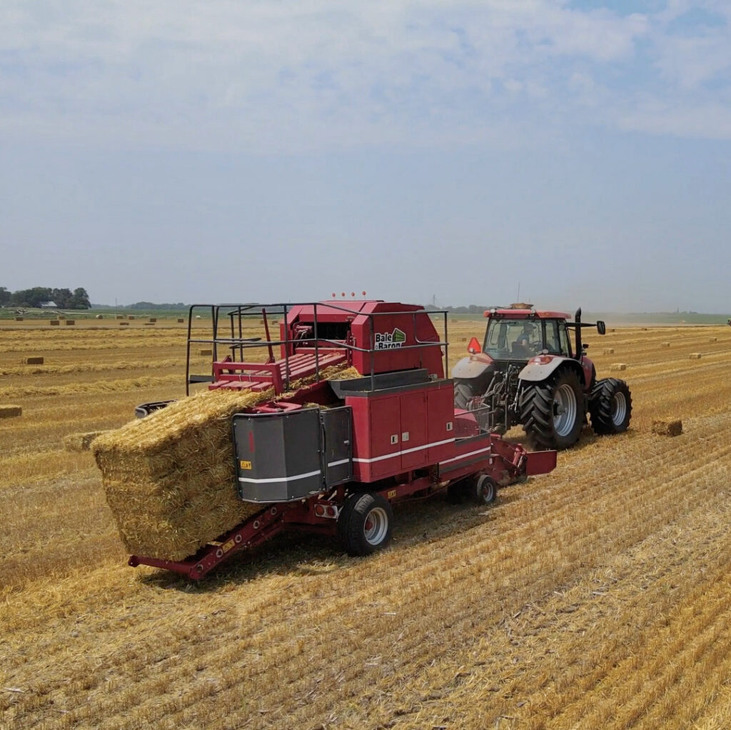 tractor bundling square bales in field
