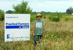 Andy Dunham stands by his Practical Farmers of Iowa sign at Grinnell Heritage Farm