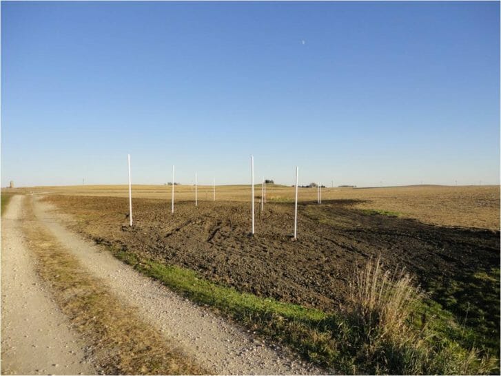 A field of recently disturbed soil with PVC piping stick out of the ground, indicating the location of the finished bioreactor.